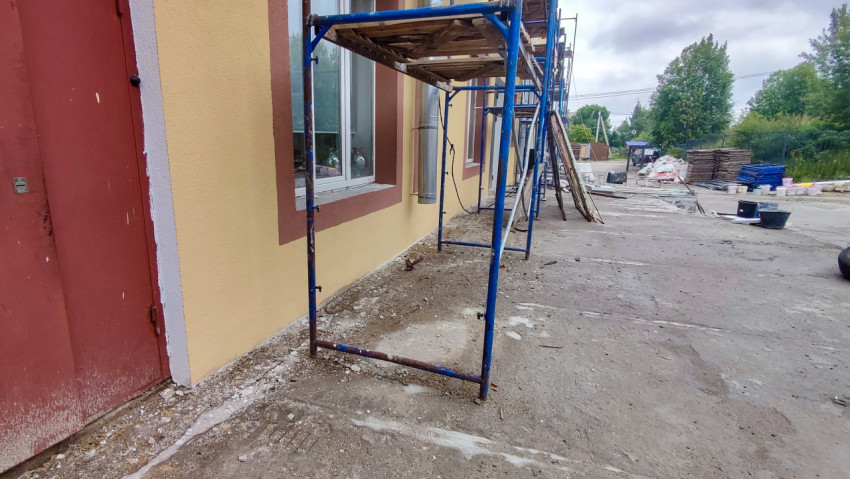 Строительные леса и материалы у фасада здания на огражденной рабочей зоне