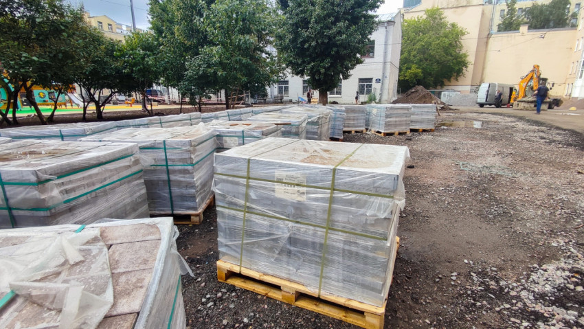 Строительная техника и паллеты с плиткой на дворовой площадке ремонта