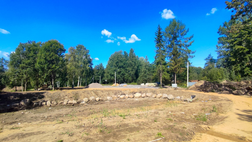 Расчищенная площадка в лесопарке с каменной кромкой и песчаным маршрутом