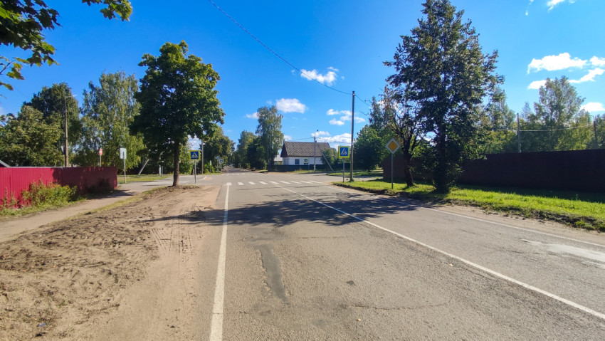 Прямая дорога к пешеходному переходу с песчаной обочиной и дорожными знаками