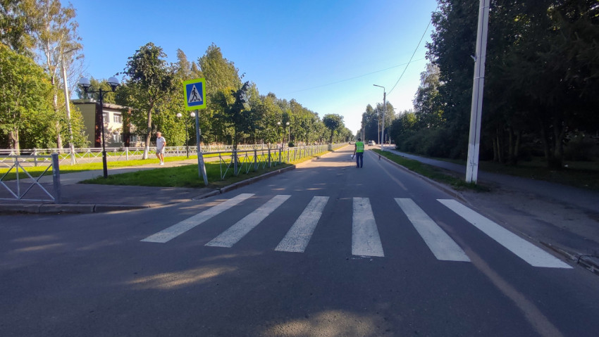 Зебра на дороге и знак перехода, а парень в жилете идёт вдоль ограждения