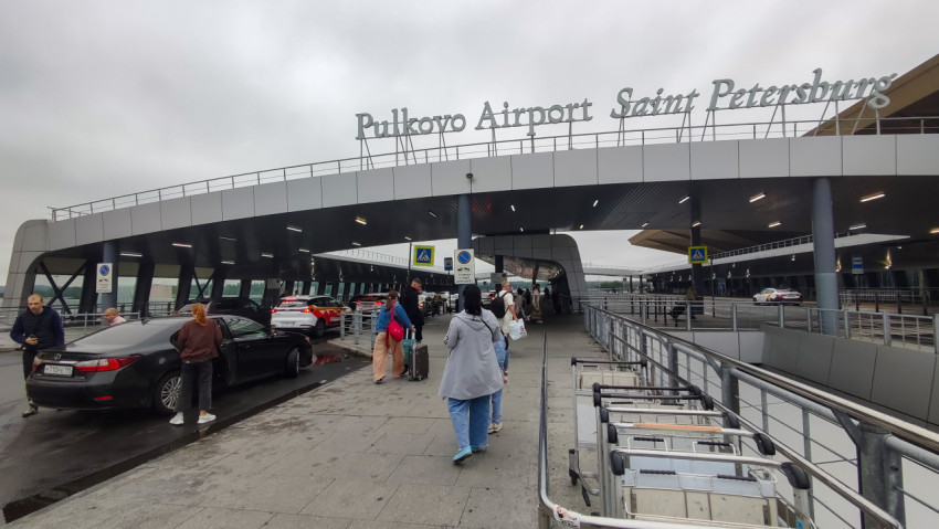 Под навесом Пулково видна длинная линия подъезда и поток пассажиров