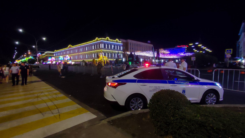 Полицейская машина с мигалками у празднично подсвеченной улицы