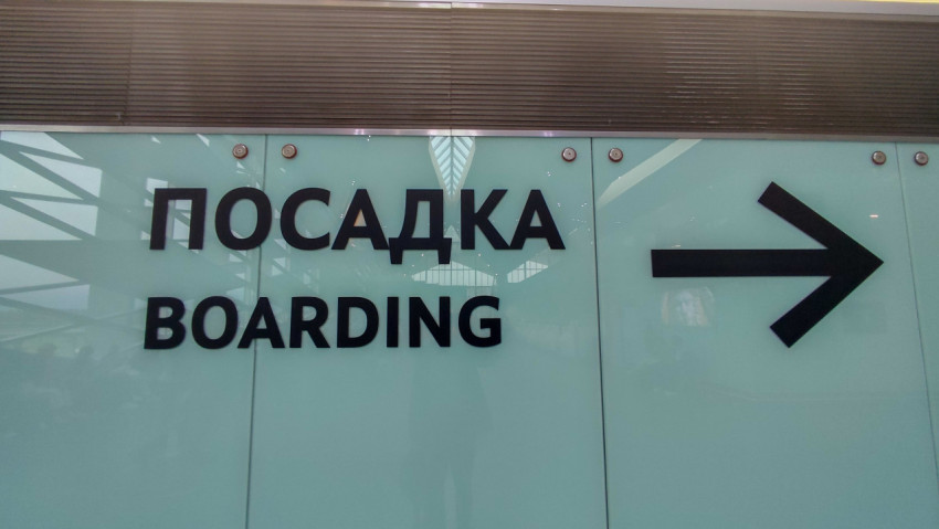 «Посадка / Boarding» и стрелка на стеклянной стене терминала