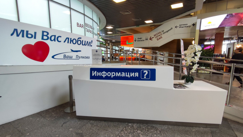 Стойка «Информация» в аэропорту на фоне баннера «Мы вас любим!»
