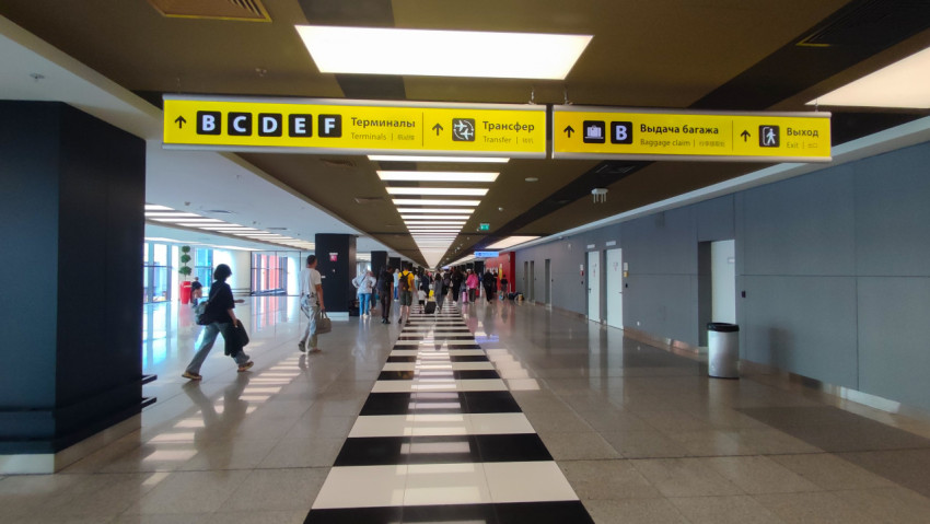 Толпа в коридоре терминала под жёлтыми табло направлений