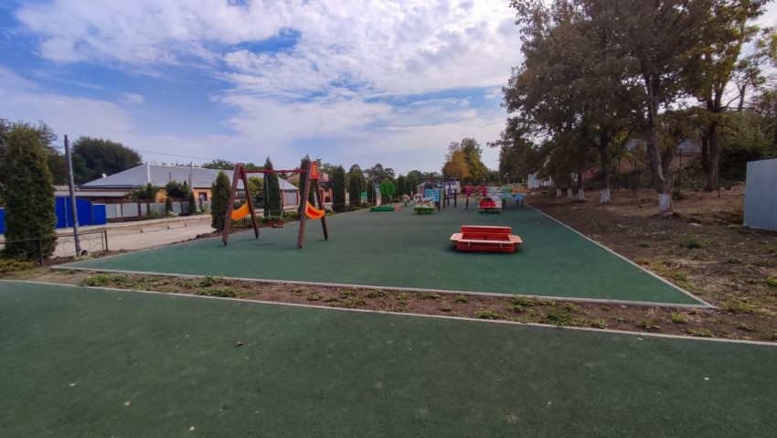 Детская площадка с качелями на зелёном резиновом покрытии