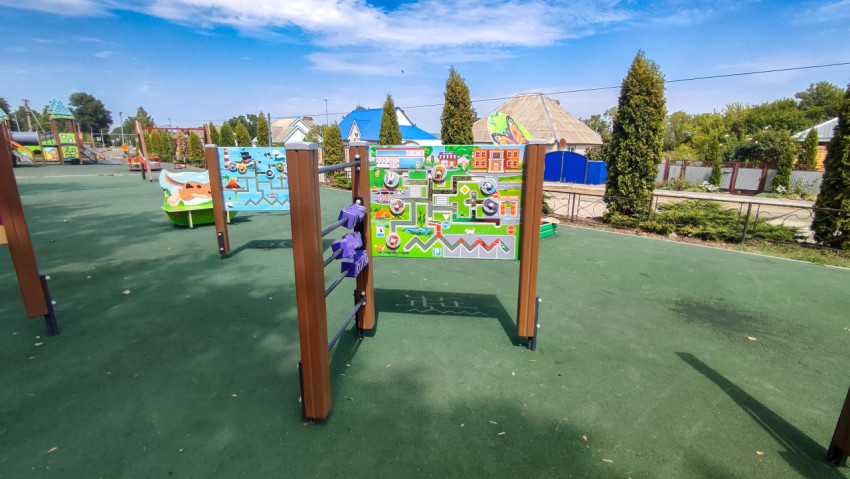 Развивающие панели с лабиринтами на зелёном покрытии детской площадки