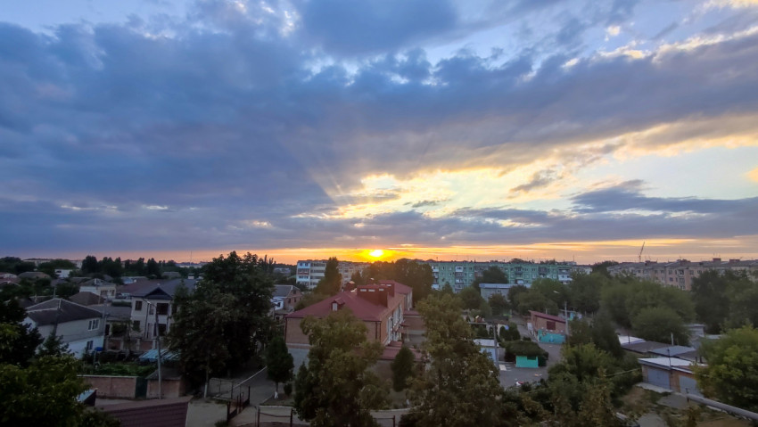 Широкий закатный вид с лучами солнца над смешанной городской застройкой