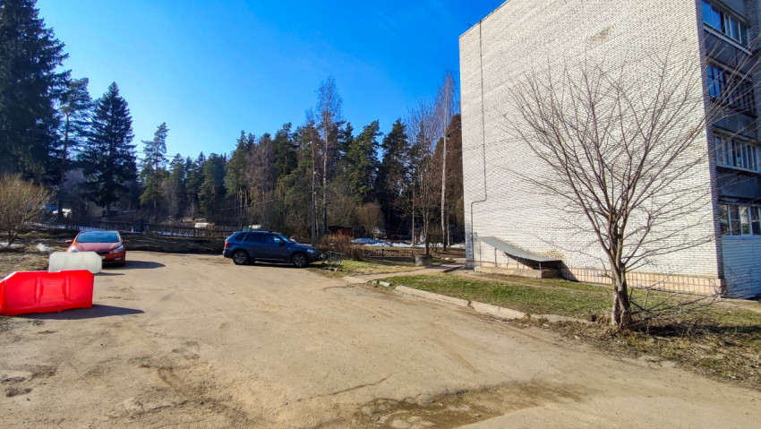 Парковка у торца жилого дома рядом с лесом
