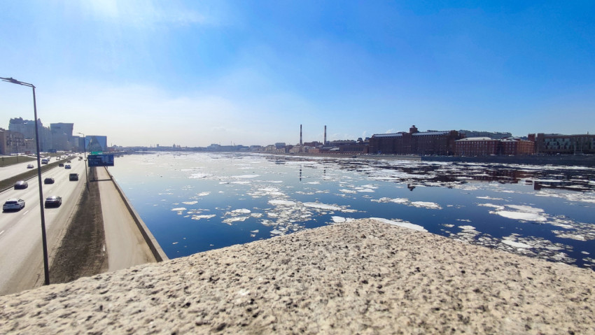 Река Нева с ледяной шугой и отражением труб на фоне городской застройки