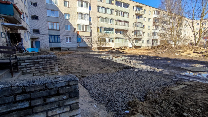 Двор жилого квартала с насыпью щебня и остатками снега весной