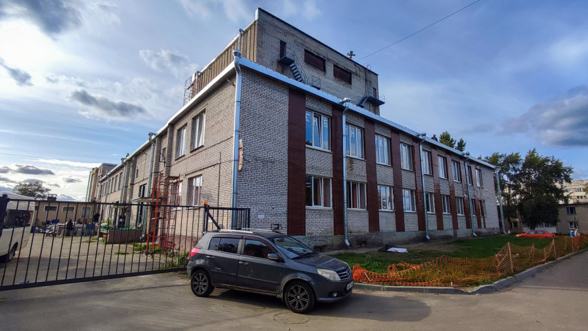 Кирпичное административное здание с автомобильной стоянкой и строительными работами