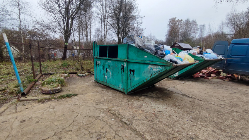 Мусорный контейнер с бытовыми отходами на бетонной площадке