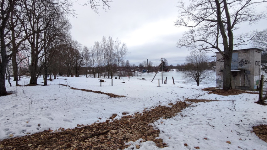 Снег и замёрзший пруд в окружении деревьев и старого здания