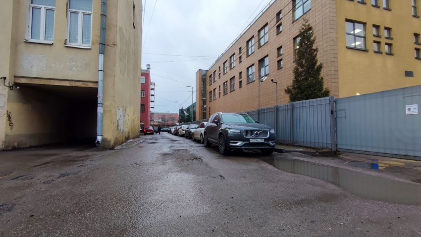 Узкий проезд между зданиями с припаркованными машинами