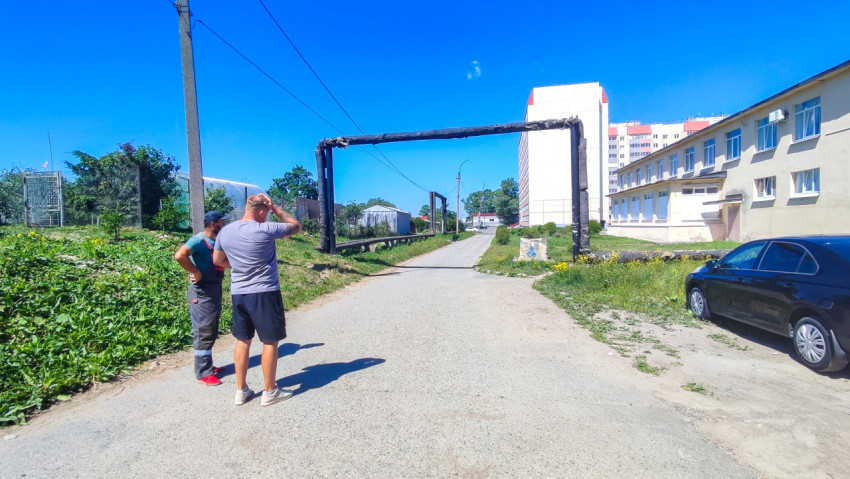 Двое мужчин стоят на дороге под рамной эстакадой трубопровода