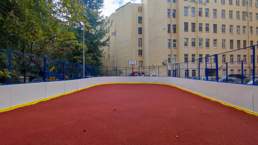 Пустая дворовая площадка с красным покрытием и баскетбольным кольцом