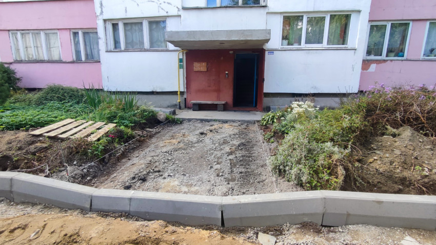 Подъезд жилого дома и подготовка дорожки с щебнем между клумбами и бордюром