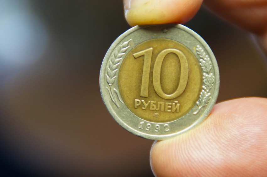 В пальцах зажата биметаллическая российская монета номиналом 10 рублей, отчеканенная в 1992 году