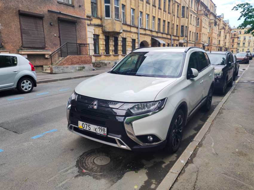 Белый Mitsubishi Outlander на парковке у жилых домов, номер частично закрыт
