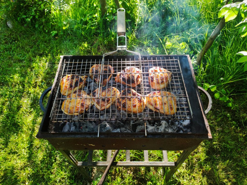 Мангал с курицей на решётке на фоне зелёной травы, вид сверху