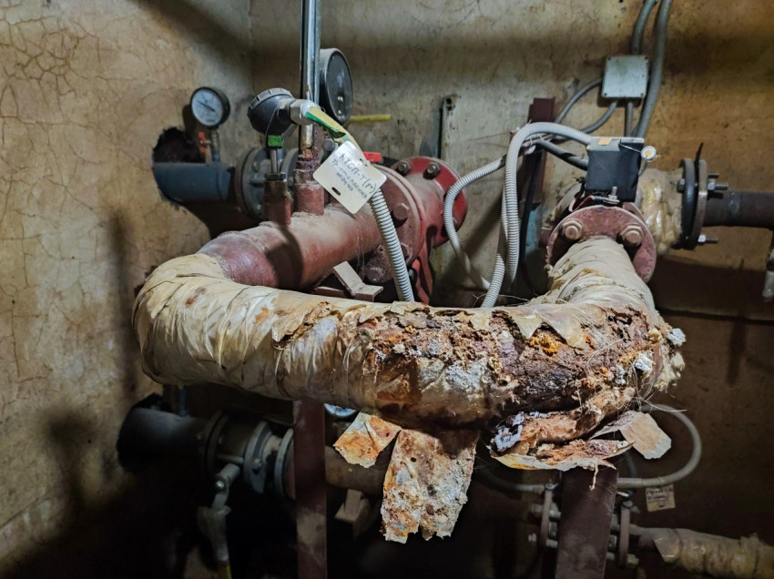 Ржавое колено трубопровода с разрушенной теплоизоляцией и датчиками контроля