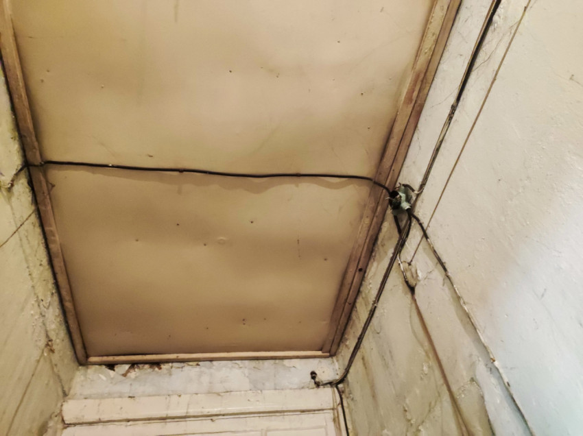 Потолочная панель в деревянной раме и открытая электропроводка на стене