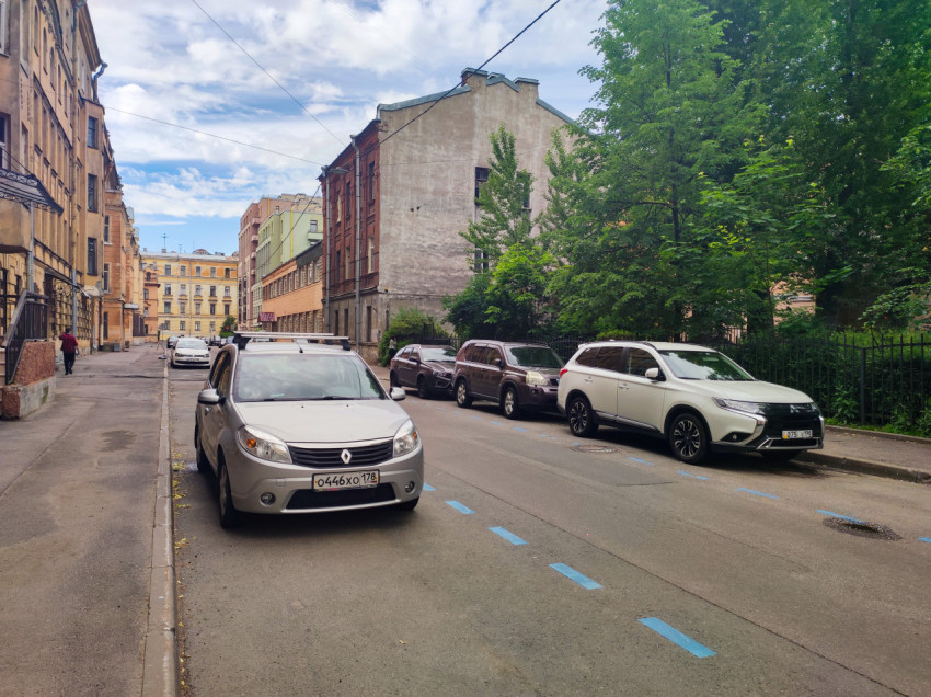 Тихая улица Санкт-Петербурга с припаркованными автомобилями, деревьями и фасадами старой застройки