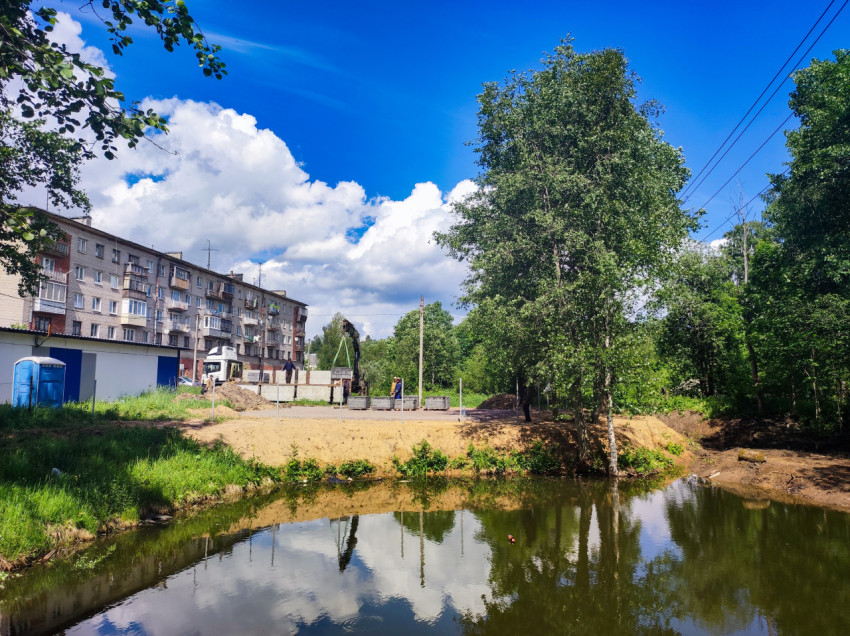 Пруд у жилого дома и разгрузка поддонов с блоками краном-манипулятором