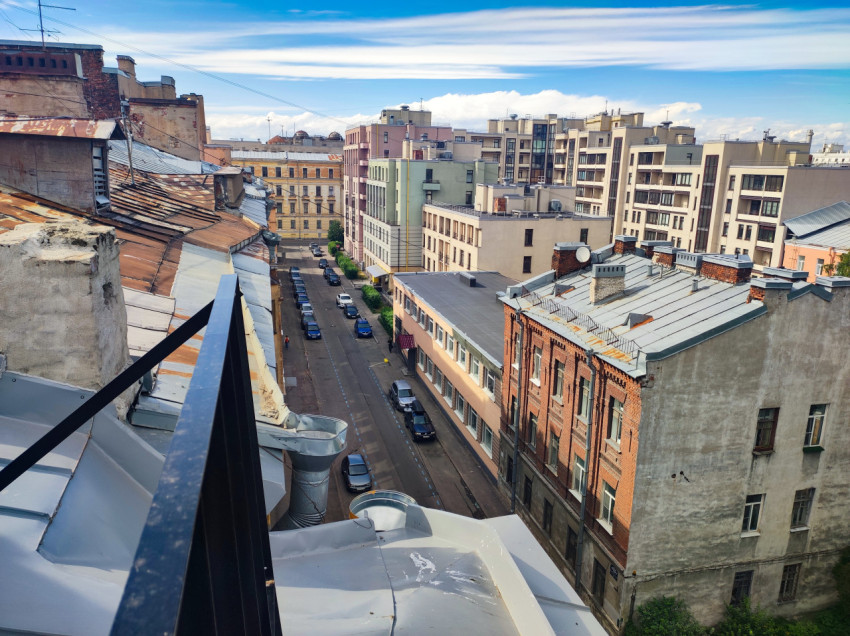 Вид с крыши на улицу с парковкой и смешанной городской застройкой