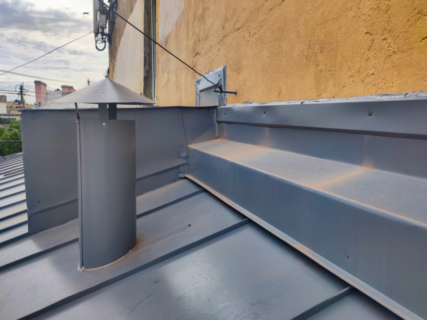 Примыкание металлической кровли к стене с вентиляционным выводом и крепёжным узлом