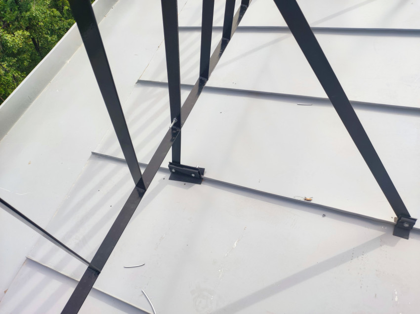 Чёрная металлическая рама на металлической кровле с крепежом