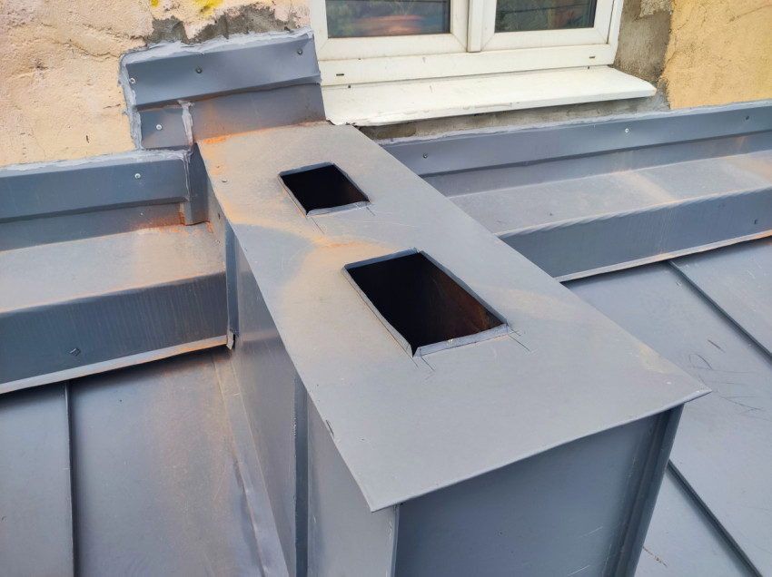 Металлический вентиляционный короб с двумя отверстиями на крыше у окна
