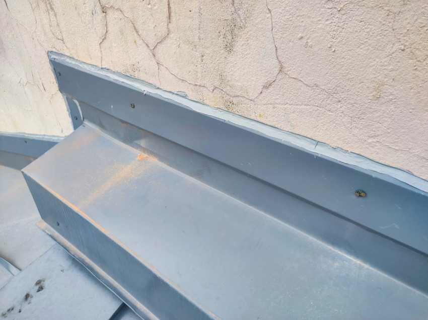 Узел примыкания металлического фартука к стене на фальцевой кровле, крупный план
