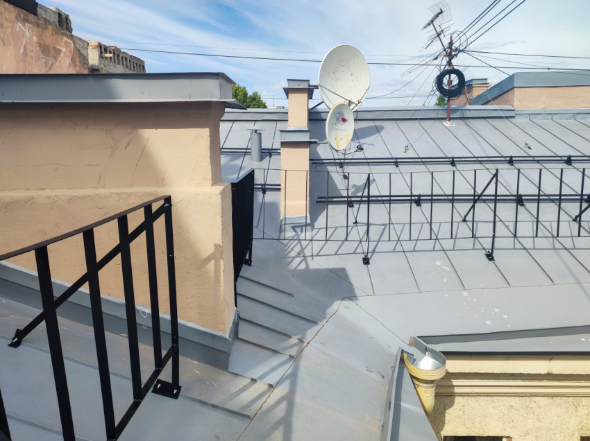 Спутниковые антенны и снегозадержатели на фальцевой крыше рядом с дымовыми каналами