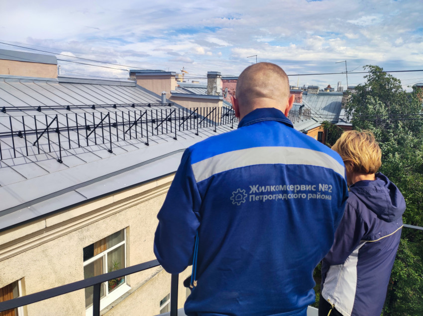 Осмотр металлической кровли сотрудниками Жилкомсервиса на крыше дома