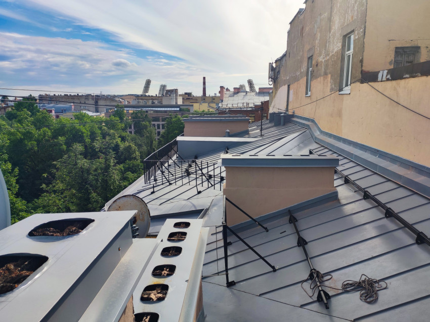 Металлическая крыша с вентиляционными коробами, креплениями и видом на квартал