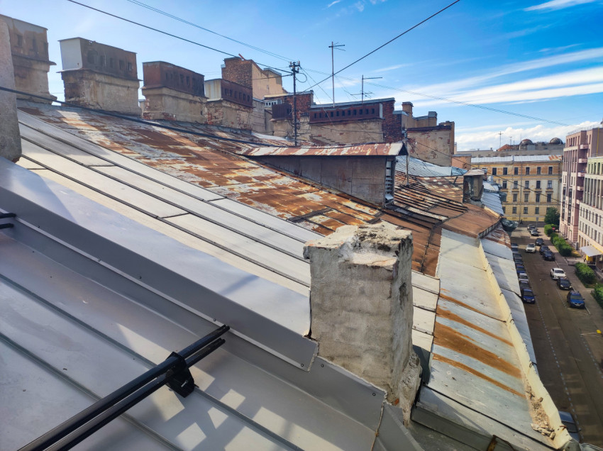 Ржавый участок металлической крыши с дымовыми трубами и антеннами