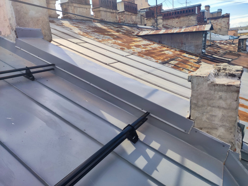 Металлическая фальцевая кровля с ограждениями и соседними ржавыми крышами