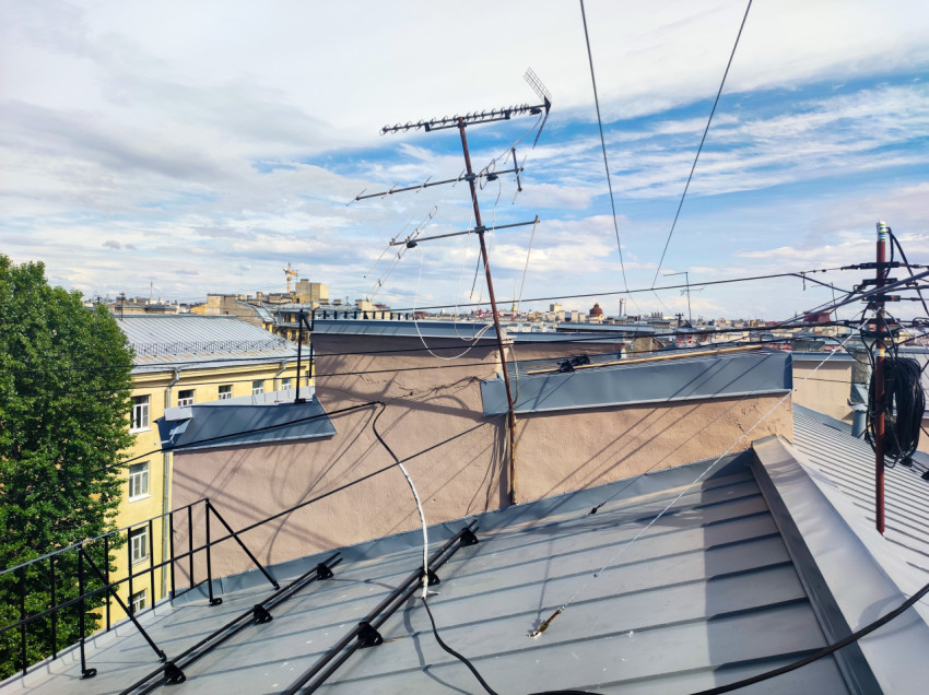 Телевизионные антенны и кабели на крыше с видом на городскую панораму