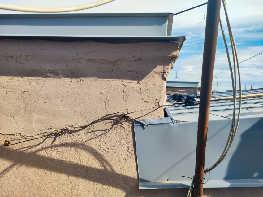 Парапет крыши с металлическим колпаком и проводами крупным планом