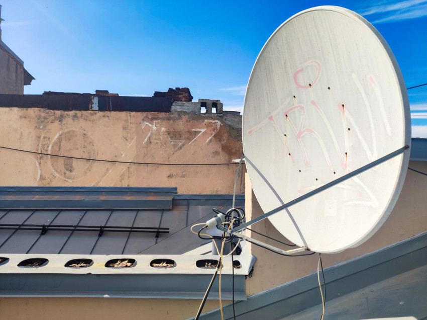Спутниковая антенна у старого парапета на крыше на фоне неба