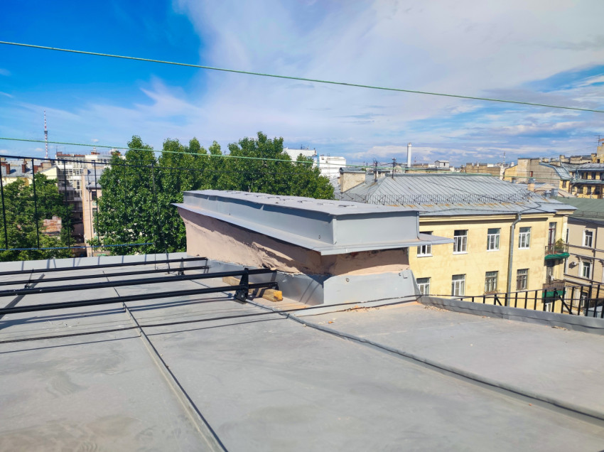 Узел на крыше с оштукатуренной надстройкой под металлическим колпаком и ограждением по периметру