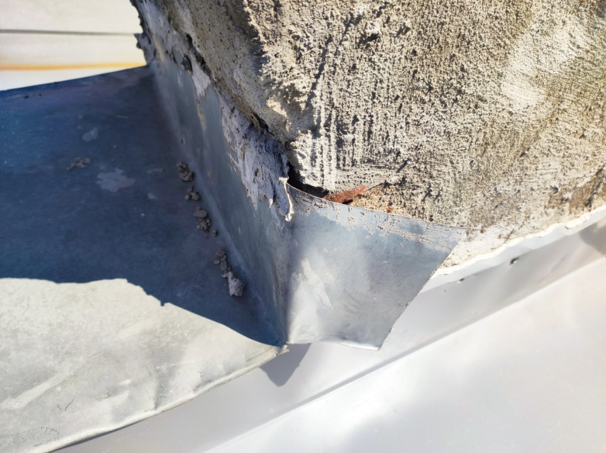 Угловой элемент фартука у основания трубы с коррозией и крошением штукатурки