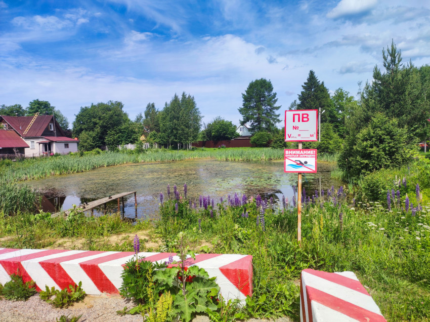 Пожарный пруд с табличкой «ПВ», знаком «Купаться запрещено» и бетонными блоками