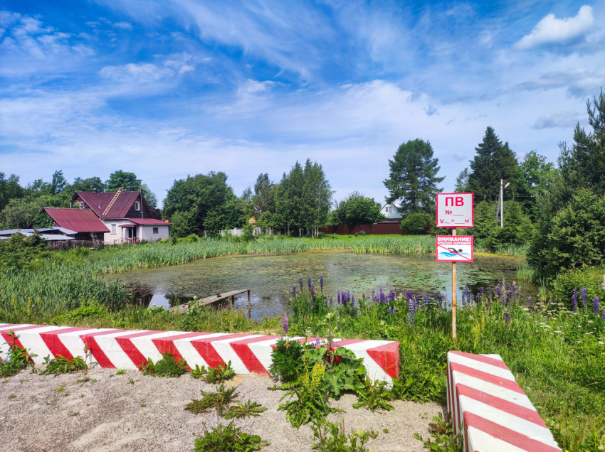 Сельский пруд у частных домов с табличкой «ПВ» и предупреждением о запрете купания