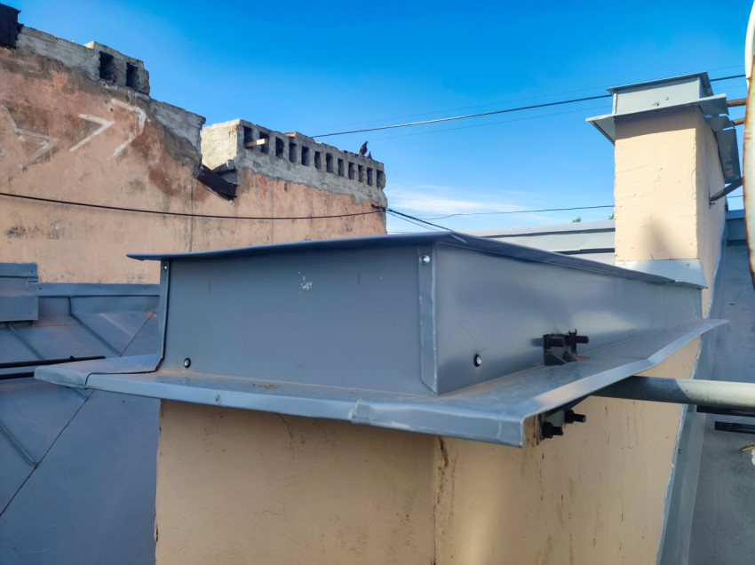 Вентиляционная шахта с металлическим колпаком и проводами над кровлей