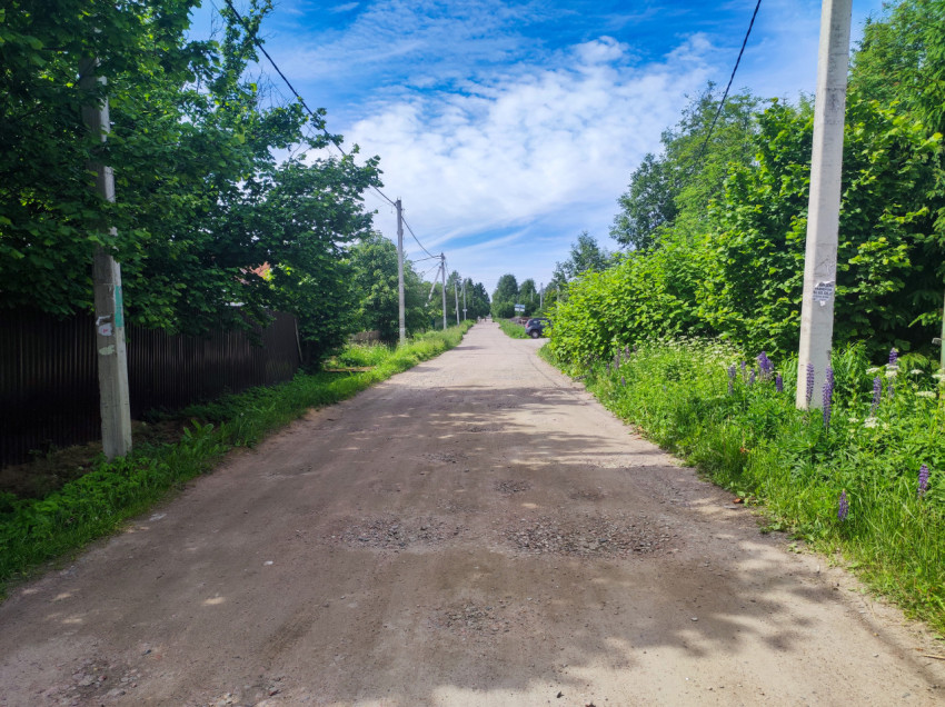 Тихая сельская улица с асфальтированной дорогой и линией электропередачи