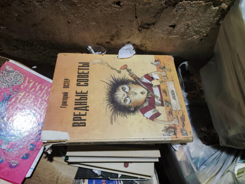 Книга Григория Остера «Вредные советы» на стопке макулатуры у бетонной стены